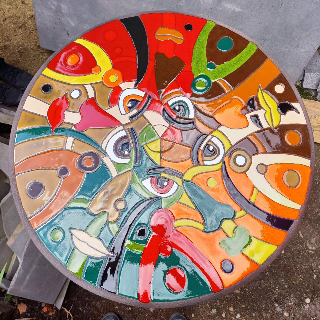 Table bistrot en pierre de lave émaillée avec motifs de visages intriqués après cuisson (photo par L'île o Pierres).
